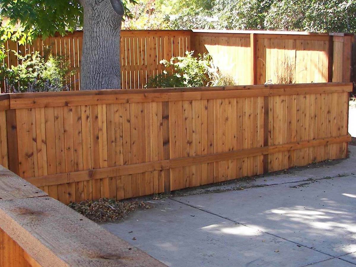 Wood stockade fence with cap and trim installed around a gardening area in Colorado